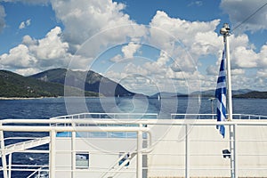 The Greek flag on the ship against the background of the sea of islands. Sea voyage in the Ionian sea.