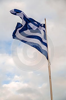 Greek flag waving on a flag pole against the sky