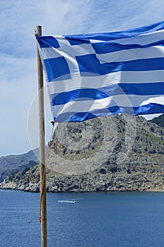 Greek flag waving in the wind and mount Tsambika