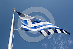 Greek flag in the wind against a blue Summer sky
