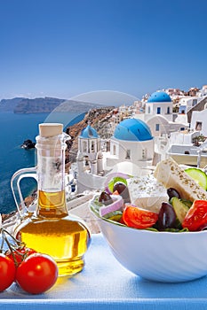 Greek food against famous churches in Oia village on Santorini island in Greece