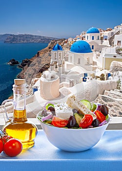 Greek food against famous churches in Oia village on Santorini island in Greece