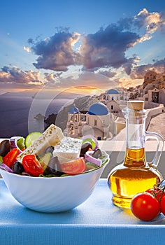 Greek food against famous churches in Oia village on Santorini island in Greece