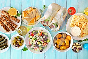 Greek food table scene, overhead view on a blue wood background