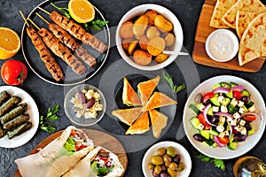 Greek food table scene, top down view on a dark background