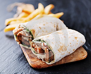 Greek gyro wrap cut in half and served with fries