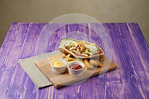 Greek gyros with fries and nuggets on a wooden board with two cups of ketchup and cheese on table