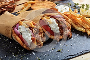 Greek gyros wrapped in pita breads on a black dish