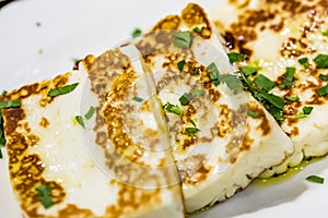 Greek haloumi cheese on white plate, closeup.