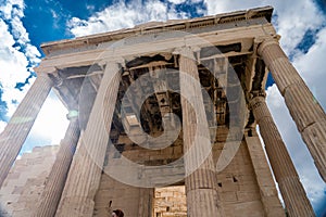 Greek iconic temple with Columns on blue, cloudy sky background. History, travel concept.