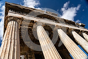 Greek iconic temple with Columns on blue, cloudy sky background. History, travel concept.