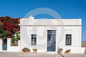 Greek Island, Cyclades. Whitewashed wall blue door and window, pot with plant, red bougainvillea