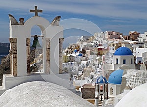 Greek Islands style white bell-tower and blue domes of the church at Oia village, Santorini island