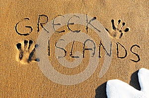 Greek islands written on sandy beach