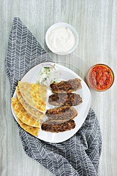 Greek Kebabs, pita bread ,chopped onion , yogurt and tomato sauce in bowls