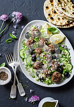 Greek lamb meatballs with avocado greek yogurt sauce, couscous and whole grain flatbread on a dark background, top view. Mediterra