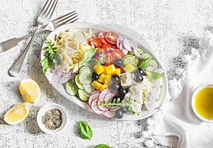 Greek lemon orzo salad. Feta, orzo, tomatoes, cucumbers, radishes, olives, peppers salad on a light background, top view. Healthy