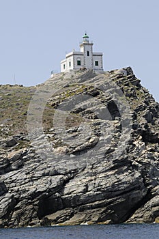 Greek lighthouse on top of rocky cliff at Paros Greece