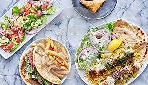 Greek meal with chicken souvlaki platter, gryos, french fries, salad and baklava