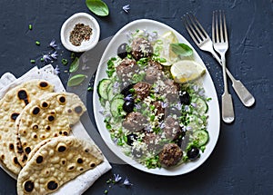 Greek meatballs with avocado greek yogurt sauce, couscous and whole grain flatbread on a dark background, top view. Mediterranean
