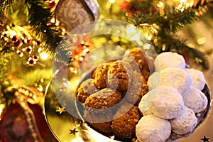 Greek melomakarona and kourabies in front of the Christmas tree - traditional Christmas cookies with honey and nuts and sugar buns