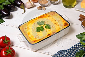 Greek Moussaka in casserole dish with the ingredients.