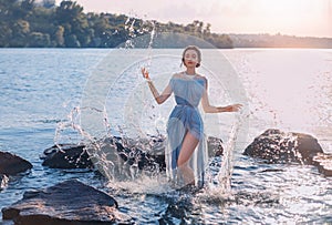 Greek mythical fairytale fantasy woman goddess nymph emerges from lake. Splashes of water. Vintage blue long sexy wet