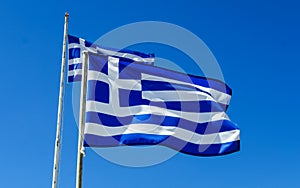 Flags of Greece Flying in Wind and Blue Sky