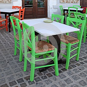 Greek outdoor cafe with green wooden chairs, Crete, Greece