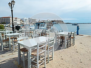 Greek outdoors tavern at port seaside Tinos island, Cyclades Greece. Chora town background