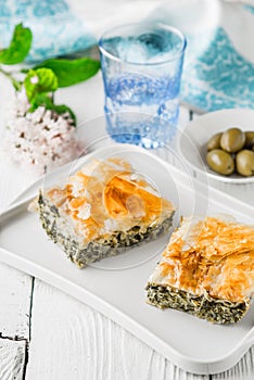 Greek pie spanakopita on the white plate with accessorizes vertical