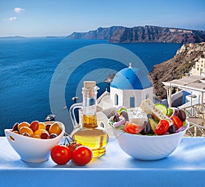 Greek salad against famous church in Oia village, Santorini island in Greece