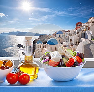 Greek salad against famous church in Oia village, Santorini island in Greece