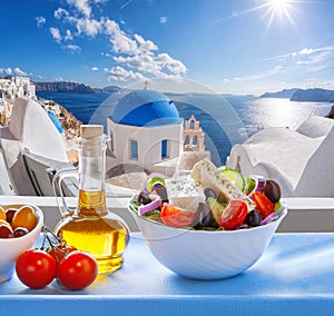 Greek salad against famous church in Oia village, Santorini island in Greece