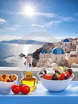 Greek salad against famous church in Oia village, Santorini island in Greece