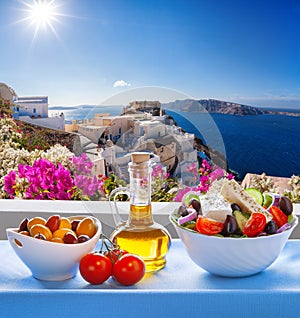 Greek salad against famous church in Oia village, Santorini island in Greece
