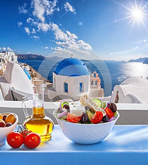 Greek salad against famous church in Oia village, Santorini island in Greece