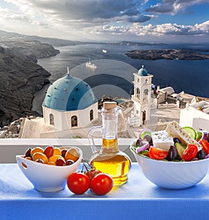 Greek salad against famous church in Thira town on Santorini island in Greece