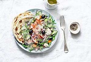 Greek salad with baked salmon on a light background, top view. Healthy mediterranean diet food