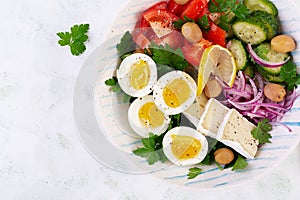 Greek salad and boiled eggs. Fresh vegetable salad with tomato, cucumbers, olives, arugula and cheese. Trendy food. Top