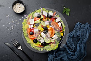 Greek salad in ceramic plate on black concrete background. Traditional Greek dish. Selective focus. Top view