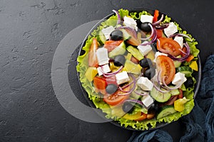 Greek salad in ceramic plate on black concrete background. Traditional Greek dish. Selective focus. Top view