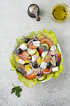Greek salad in ceramic plate on gray concrete background. Traditional Greek dish. Selective focus.Top view
