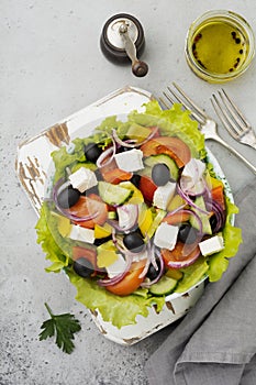 Greek salad in ceramic plate on gray concrete background. Traditional Greek dish. Selective focus.Top view