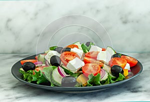 Greek salad of fresh cucumber, tomato, sweet pepper, lettuce, feta cheese and olives with olive oil. Healthy food