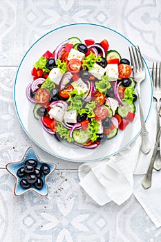 Greek salad of fresh cucumber, tomato, sweet pepper, lettuce, red onion, feta cheese and olives with olive oil