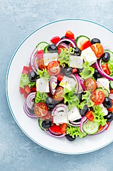 Greek salad of fresh cucumber, tomato, sweet pepper, lettuce, red onion, feta cheese and olives with olive oil