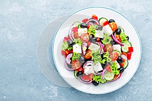 Greek salad of fresh cucumber, tomato, sweet pepper, lettuce, red onion, feta cheese and olives with olive oil