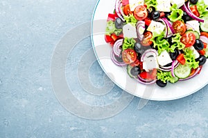 Greek salad of fresh cucumber, tomato, sweet pepper, lettuce, red onion, feta cheese and olives with olive oil