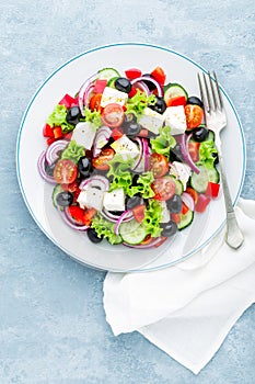 Greek salad of fresh cucumber, tomato, sweet pepper, lettuce, red onion, feta cheese and olives with olive oil